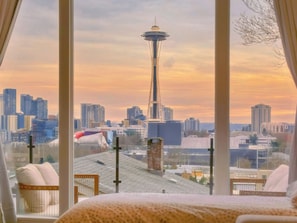 A hotel room with a view of a city skyline, including a prominent tower. - 2BR Queen Anne Home - Space Needle View + Deck (Seattle)