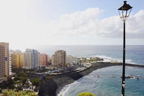 A coastal cityscape with high-rise buildings, a beach, and a lighthouse. - Studio with a View of the Harbor (Puerto de la Cruz)
