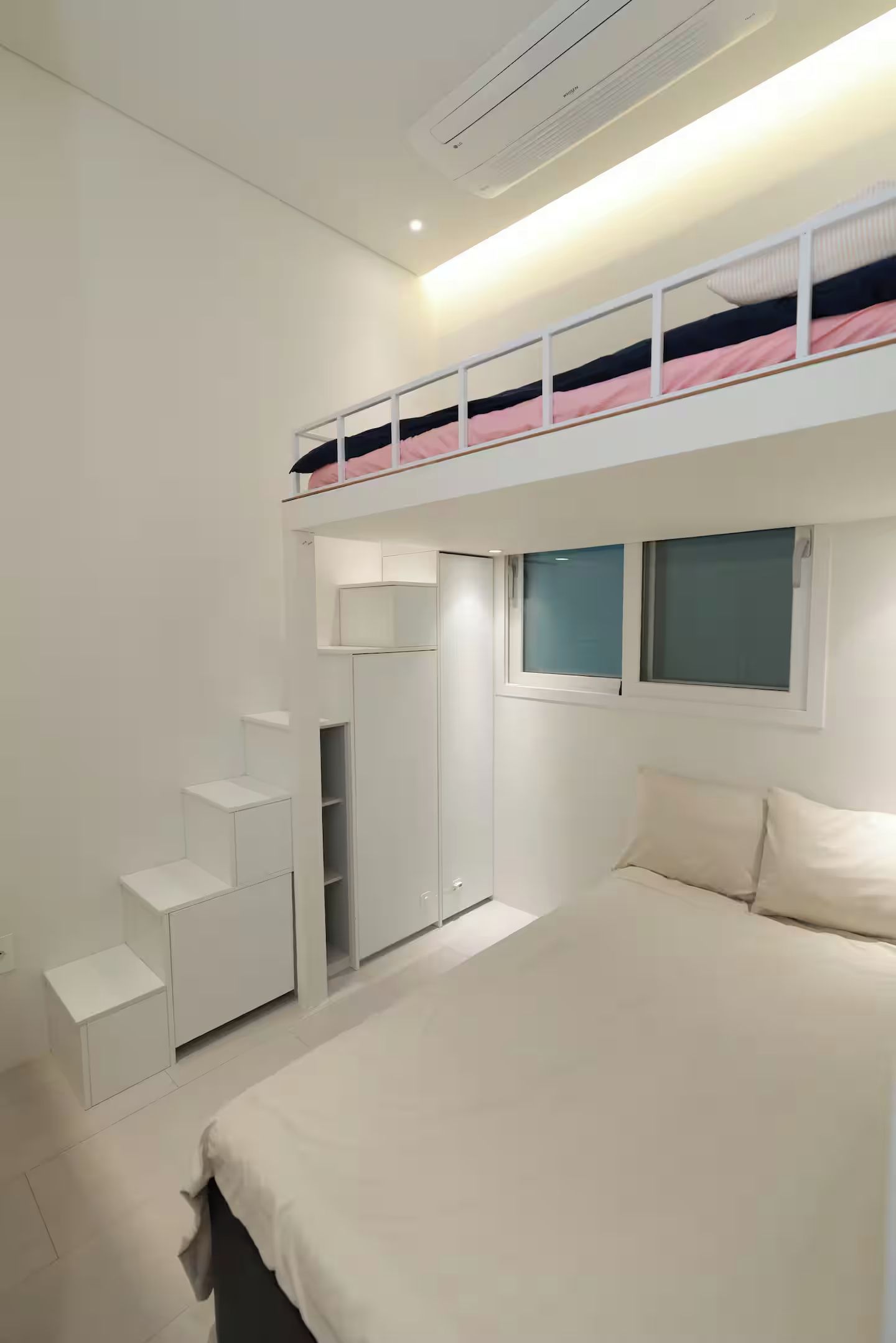 Un dormitorio con una cama nido, un armario y una mesita de noche.