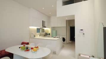 Una cocina moderna con armarios blancos, una zona de comedor con mesa para cuatro y una pequeña isla con microondas y tostadora.