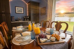 Une table mise pour le petit-déjeuner, avec une nappe, de l’assiette, des couverts et une variété d’aliments pour le petit-déjeuner.