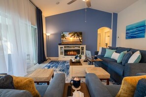 Uma sala de estar com lareira, sofá, mesa de centro e televisão.