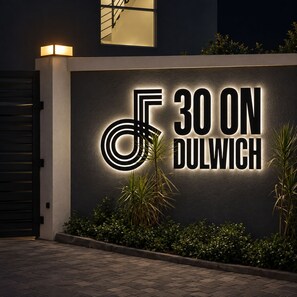 A building facade with a sign that reads '30 ON DULWICH' and a decorative element resembling a musical note. - Selah Oasis - Kingston 2BR, 3 Beds, Sleeps 5 ~ Pool, Parking & Central Location (Kingston)