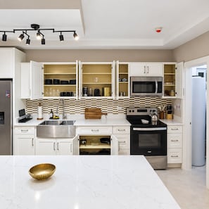 A modern kitchen with white cabinetry, a central island, and a microwave above the stove. - Selah Oasis - Kingston 2BR, 3 Beds, Sleeps 5 ~ Pool, Parking & Central Location (Kingston)