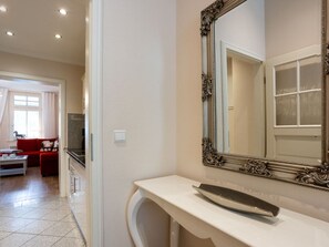 A bathroom with a large ornate mirror, a white countertop, and a red sofa in the adjacent living area. - No. 9 in Villa Aegir (Binz)