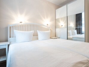 A modern hotel room with a large bed, a nightstand, a mirror, and a wardrobe. - No. 9 in Villa Aegir (Binz)