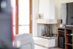 Un saló amb una llar de foc, una televisió i una porta que ofereix vista a l'exterior.