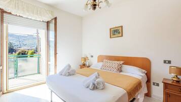Una habitación de hotel con una cama, una mesita de noche, una lámpara, un cuadro en la pared y vista a una montaña a través de la ventana.