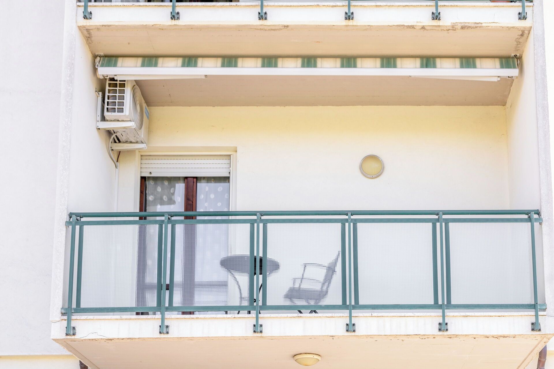 Ein Balkon mit Metallgeländer, einem kleinen Tisch und einem Stuhl.