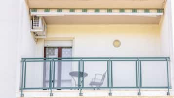 Ein Balkon mit Metallgeländer, einem kleinen Tisch und einem Stuhl.