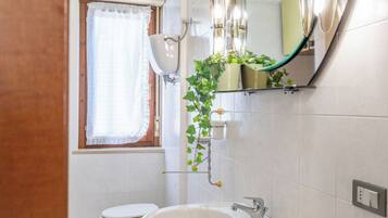 Ein Badezimmer mit Toilette, Waschbecken und einem beleuchteten Spiegel.