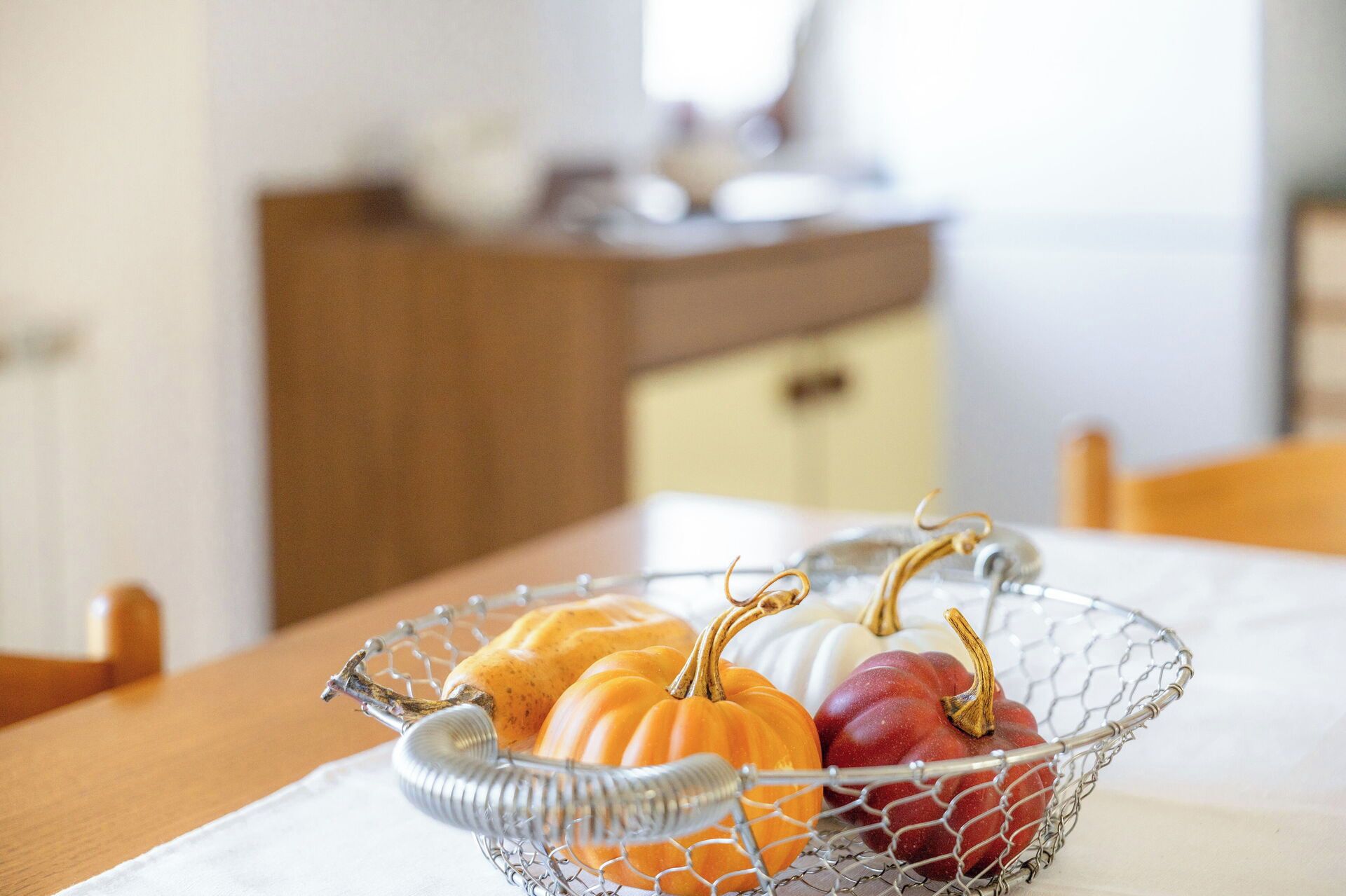 Un panier en fil métallique contenant des citrouilles, posé sur une table.
