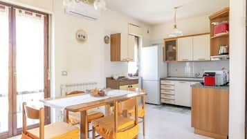 Eine Küche mit Essbereich, Holzschränken, einem Kühlschrank und einer Kaffeemaschine.