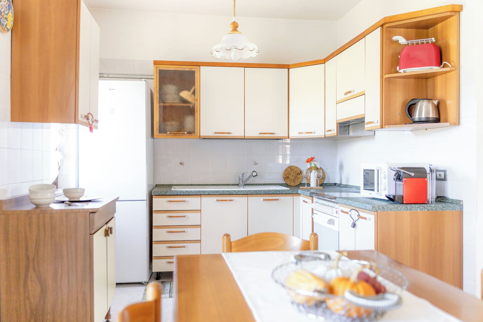 A modern kitchen with white cabinets, a granite countertop, a sink, and a dining area with a table and chairs.