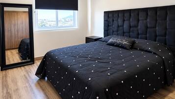 Ein Schlafzimmer mit einem großen Bett, einem Kleiderschrank, einem Fenster mit Aussicht und einem schwarzen Kopfteil.