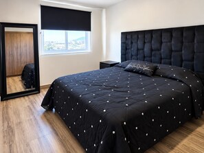 Ein Schlafzimmer mit einem großen Bett, einem Kleiderschrank, einem Fenster mit Aussicht und einem schwarzen Kopfteil.