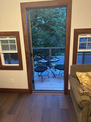 A room with a wooden floor, a sliding glass door leading to an outdoor deck with a table and chairs.