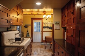 A kitchen with wooden cabinets, a white sink, and a brick floor.