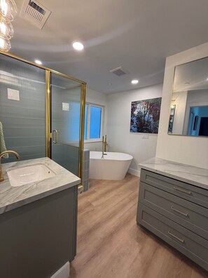 Ein modernes Badezimmer mit einer freistehenden Badewanne, einem großen Spiegel und einem Waschtisch mit Schubladen.
