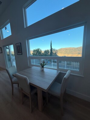 A room with a large window, a dining table, and chairs.