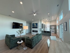 A modern living room with green sofas, a floor lamp, and a TV.