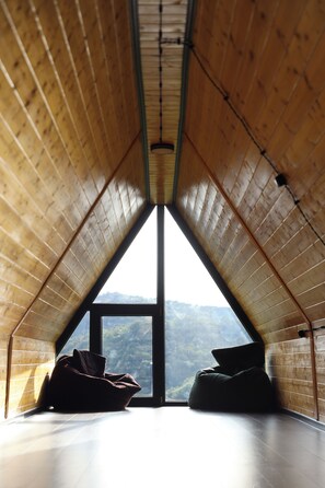 An attic room with a sloped ceiling, a large window, and two bean bags. - Lovely 4-bedroom cottage in superb Kutaisi location perfect for families (Kutaisi)