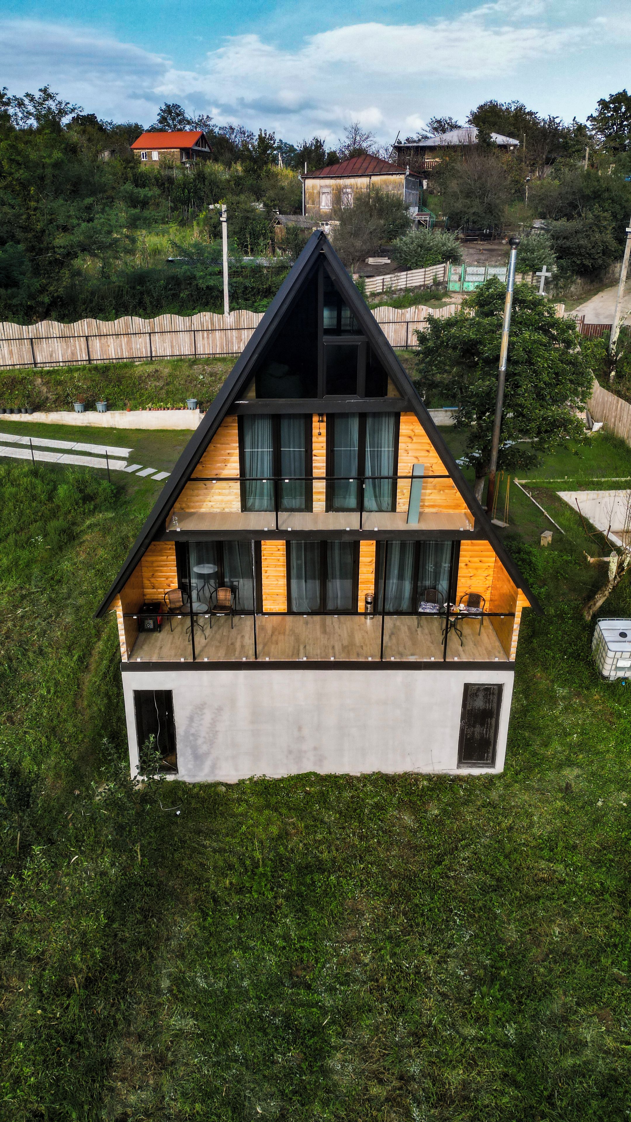 Ein modernes, zweistöckiges Haus mit einem geneigten Dach, großen Fenstern und einem Balkon.