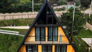 Ein modernes, zweistöckiges Haus mit einem geneigten Dach, großen Fenstern und einem Balkon.