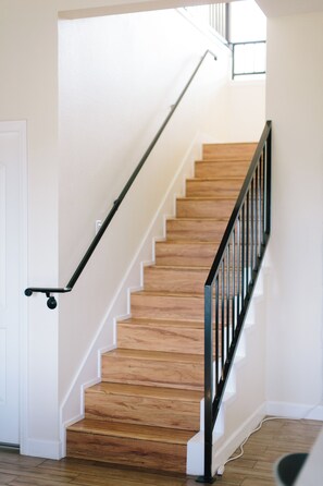 A wooden staircase with a black handrail and a white door at the bottom. - California dreamin hilltop views! 4 bedrooms & 3 full baths (Los Angeles)