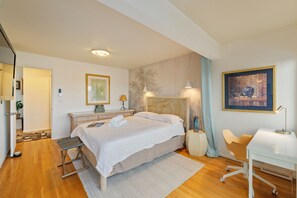 A hotel room with a bed, bedside table, desk, chair, and artwork on the walls. - Entire Queen Anne House - 3BR Space Needle View (Seattle)
