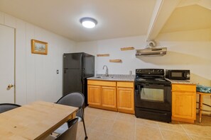 A compact kitchen with a refrigerator, stove, microwave, and wooden cabinets. - Entire Queen Anne House - 3BR Space Needle View (Seattle)
