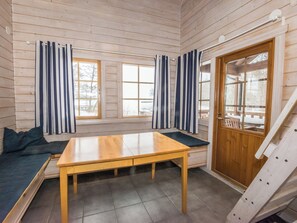 L’intérieur d’une cabane en bois, avec une table en bois, des bancs et une porte.