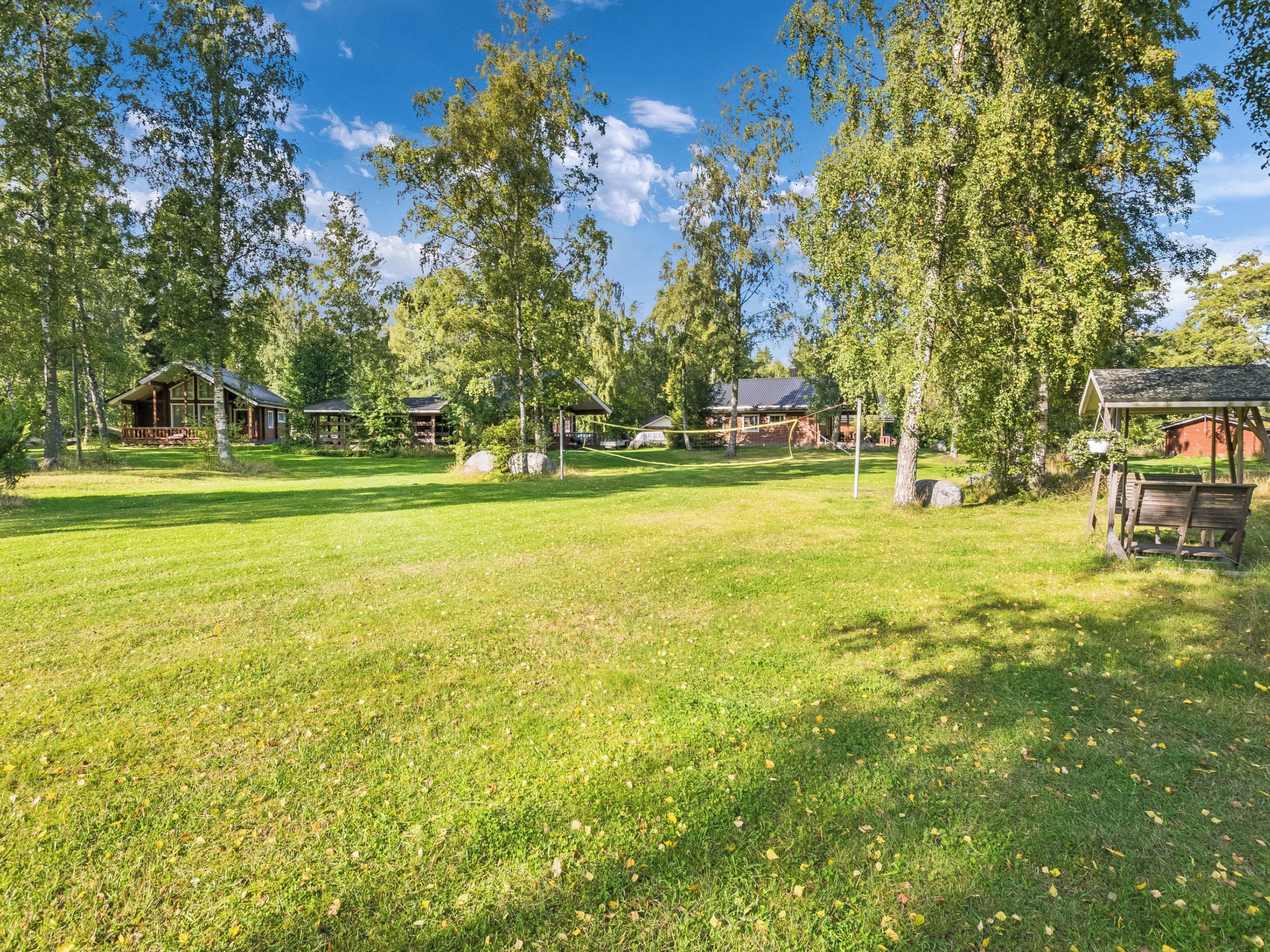 A grassy field with multiple cabins and a wooden structure.