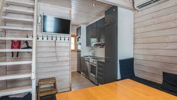 A compact kitchen with modern appliances, a wooden dining table, and a built-in TV.