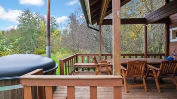 A wooden deck with a grill, chairs, and a table.