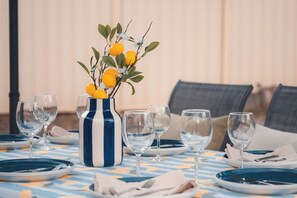 A dining table set with plates, glasses, and a striped vase with flowers. - Seednest | Spacious Magill BBQ Family Retreat (Magill)