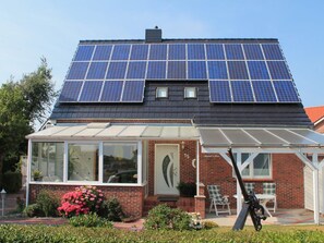Ein Haus mit Solaranlage auf dem Dach, einer überdachten Veranda und einer Ziegelstein-Fassade.