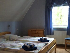 Ein Schlafzimmer mit einem Bett, einem hölzernen Schminktisch und einem Fenster mit Vorhängen.