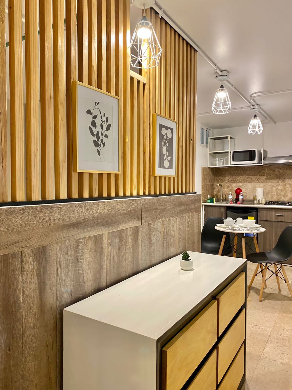 Una cocina moderna con paneles de madera, encimera blanca e iluminación colgante.