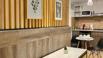 Una cocina moderna con paneles de madera, encimera blanca e iluminación colgante.