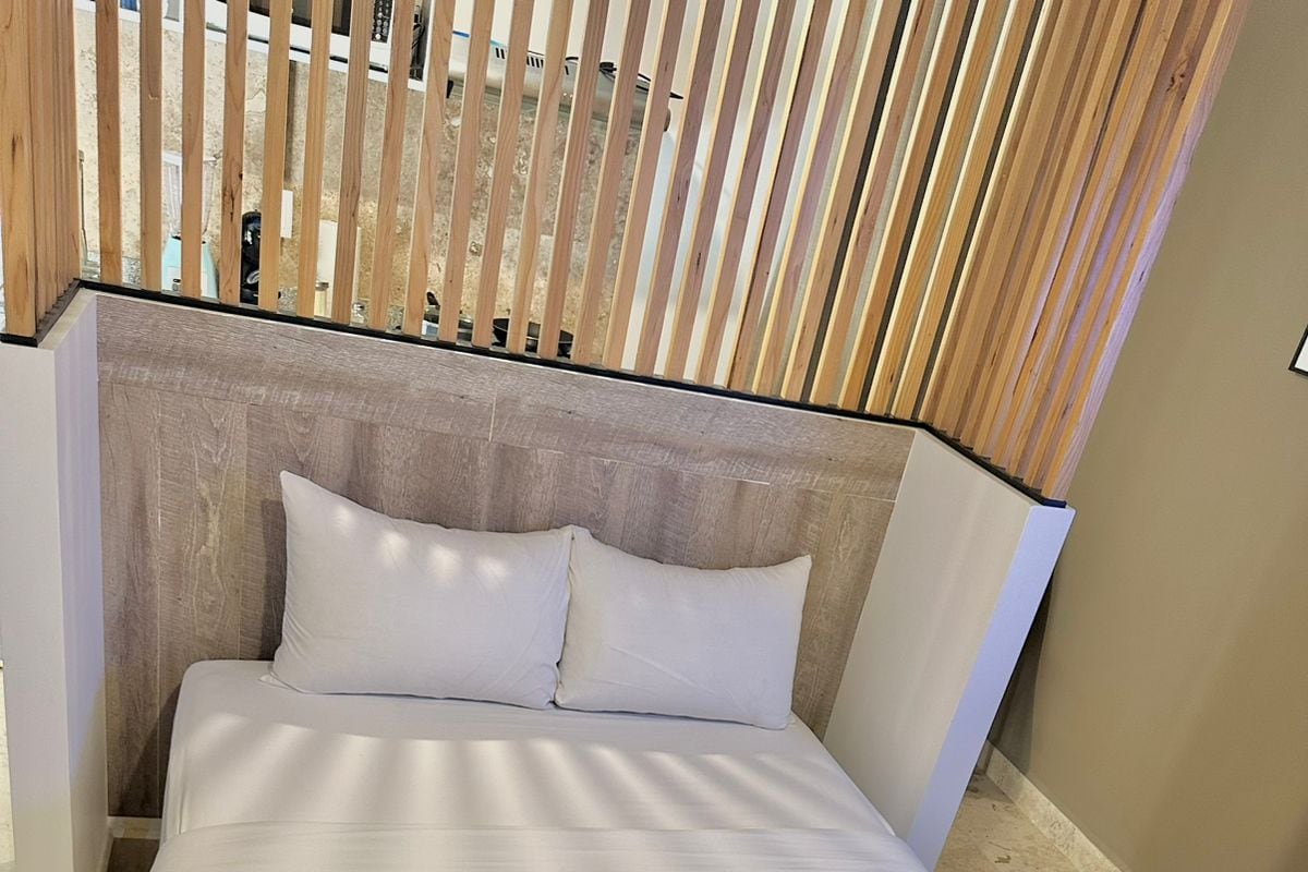 A bed with a wooden headboard, white bedding, and a folded towel on the bed.