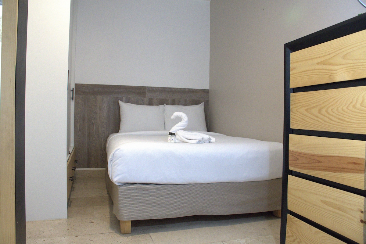 A single bed with a wooden headboard, a white pillow, and a folded towel.