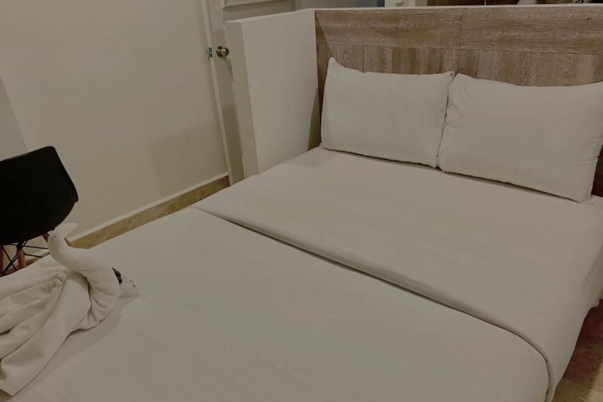 A bed with white bedding and a wooden headboard.