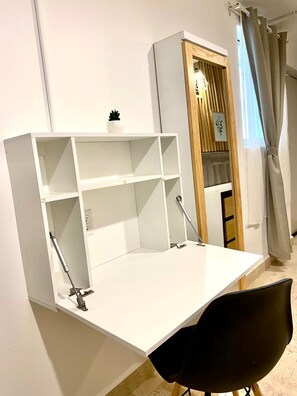 A white desk with shelves, a black chair, and a wooden cabinet with a plant. - Tamarindo by Homi Rent (Santiago de Querétaro)
