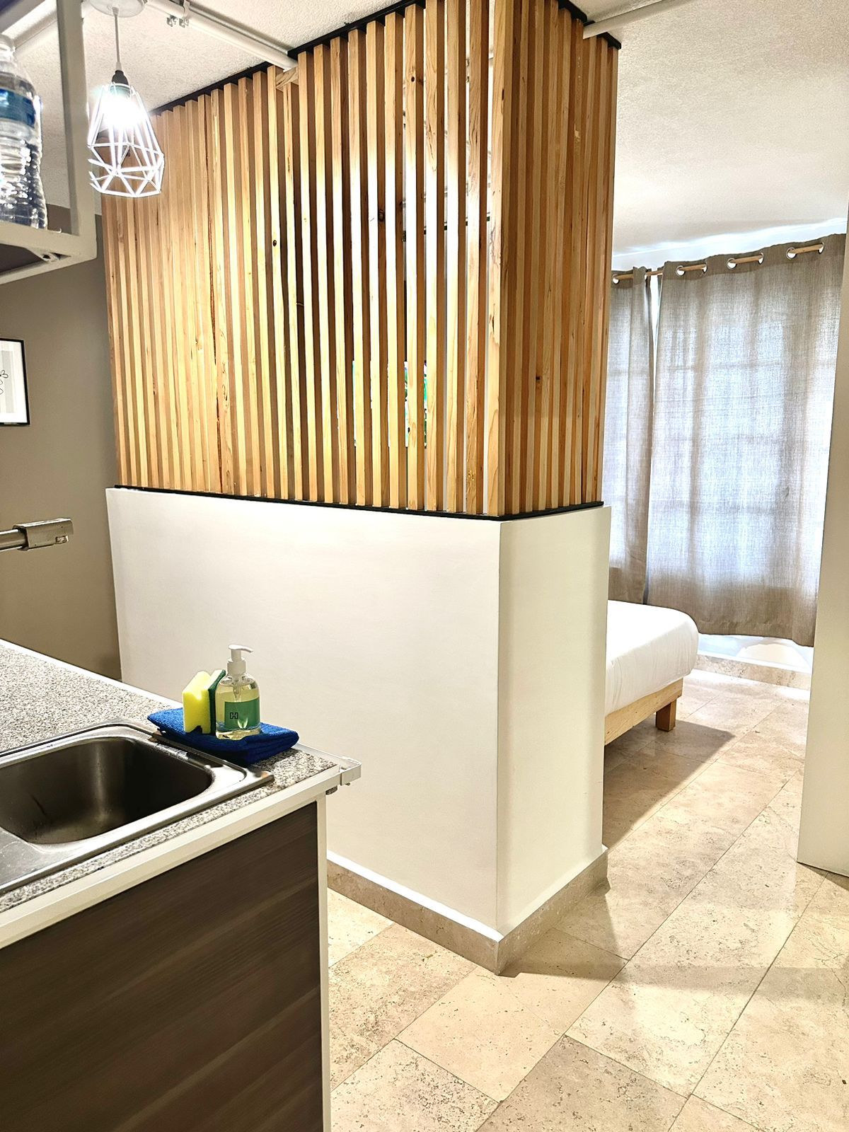 A compact room with a kitchenette, a bed, and a bathroom.