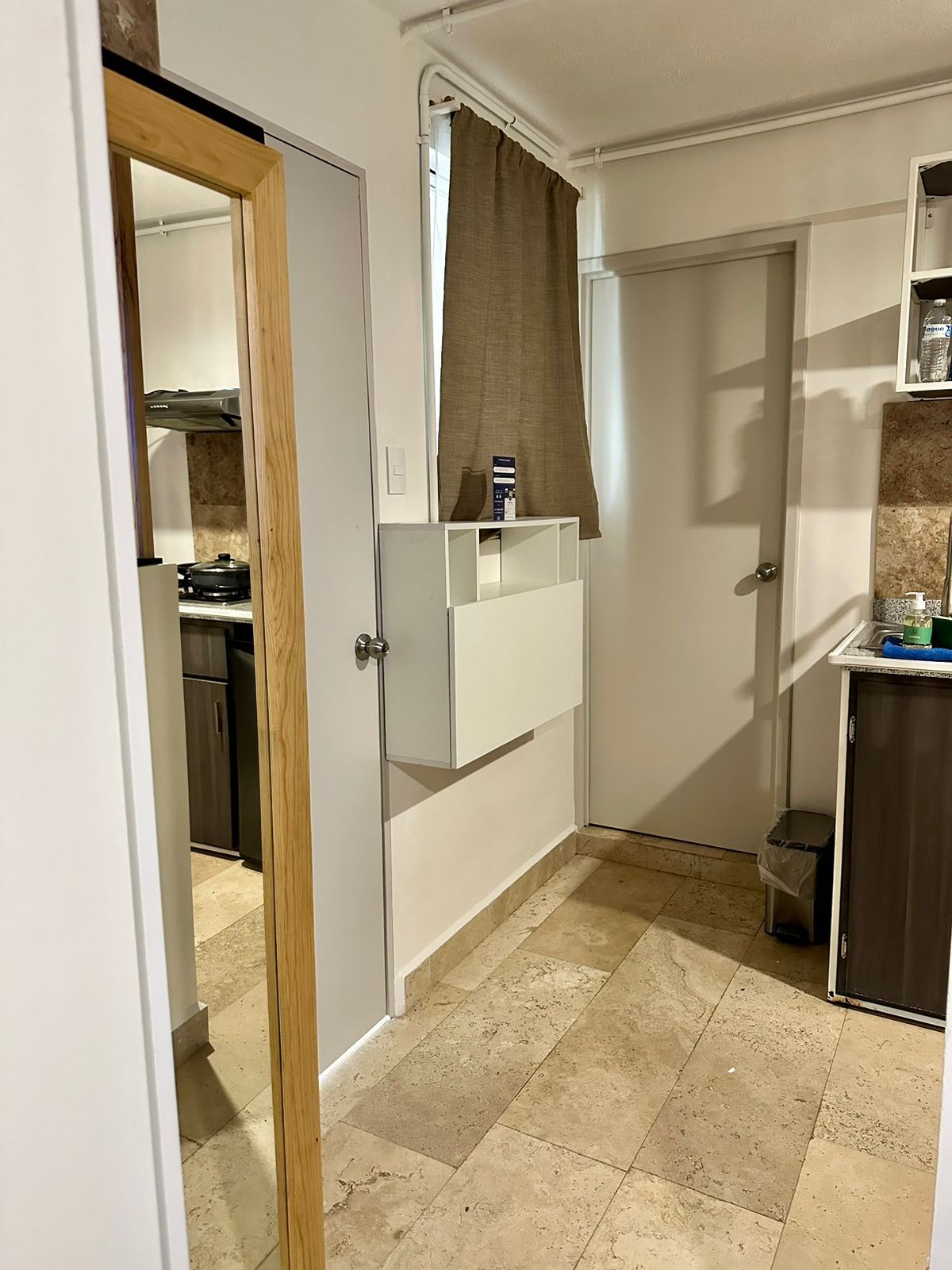 A compact kitchen with a stove, a sink, and a small trash bin.