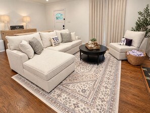 A modern living room with a sectional sofa, a round coffee table, and a patterned rug. - Walk To Tcu-Sleeps 8- 2king Beds- 2 Car Garage-Fenced Backyard (Fort Worth)