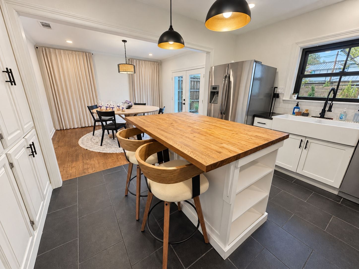 Una cocina moderna con una isla de madera, electrodomésticos de acero inoxidable e iluminación colgante.