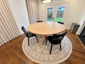 A round wooden table with four chairs, a patterned rug, and a door with a view of a backyard. - Walk To Tcu-Sleeps 8- 2king Beds- 2 Car Garage-Fenced Backyard (Fort Worth)