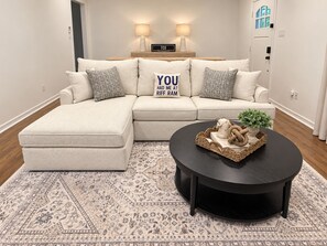 Una sala moderna con un sofá modular, una mesa de centro redonda y una alfombra estampada.